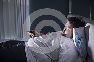 Asleep obese man in bedroom during watches TV