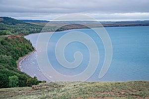 Aslykul - the largest lake in Bashkiria in cloudy weather with gray sky and blue water and a rocky shore