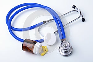 Asorted pils and a stethoscope on white background