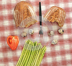 Asparagus, bread, and quail eggs on checkered tablecloth