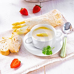 Asparagus cream soup with capers and fresh baguette photo