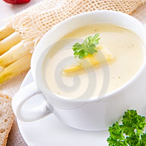 Asparagus cream soup with capers and fresh baguette photo