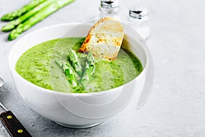 Asparagus cream soup with croutons on gray stone background