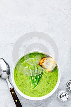 Asparagus cream soup with croutons on gray stone background