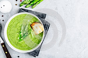 Asparagus cream soup with croutons on gray stone background