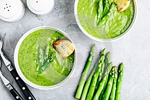 Asparagus cream soup with croutons on gray stone background