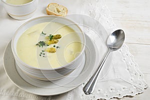 Asparagus cream soup with parsley garnish in a bowl on a white w