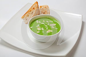 Asparagus cream soup in white bowl with bread