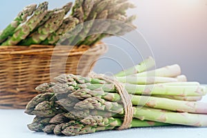 Asparagus. Fresh raw organic green Asparagus sprouts closeup. Basket and bunch n the table. Healthy vegetarian food