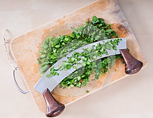 Asparagus and parsley on cutting board with mincing knife on woo