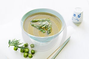 Asparagus soup in a bowl with fresh cream, dill and chive