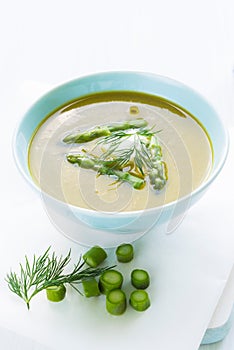 Asparagus soup in a bowl topped with fresh cream, dill and chive