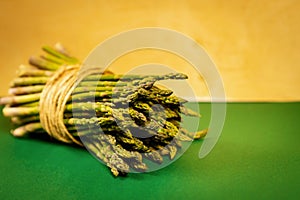 Asparagus tied with a thin string on a yellow summer background