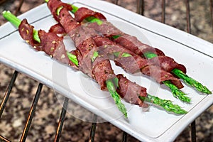 Asparagus wrapped in bacon with spices, grilled on paper for baking