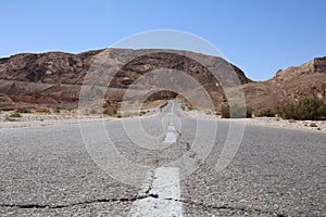 Asphalt gray road for car under blue sky in the desert way wasteland during journey to Eilat Breaks in the road