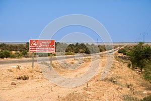 Asphalt highway in the desert with red sign of the passage of camels