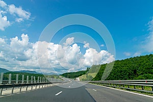 Asphalt highway and green nature landscape on a sunny day with blue sky in Romania