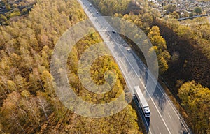 Asphalt highway or motorway autumn road in countryside with car and truck traffic Cargo Semi Trailer Moving. Aerial Top View