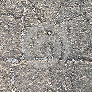 Asphalt with large cracks strewn with small broken glass. Abstract textural background.