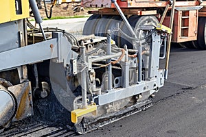 Asphalt laying equipment. Work on the device of a new road surface in a modern city. Powerful construction equipment for