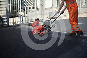 Asphalt laying. Leveling the road. A worker compresses warm asphalt