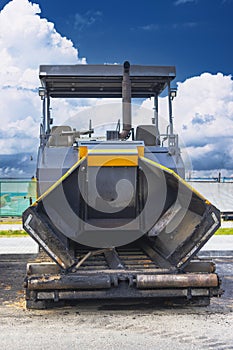 Asphalt laying machine close-up. A paver finisher, asphalt finisher or paving machine placing a layer of asphalt. Repaving the