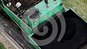 An asphalt paver is laying new asphalt on top of an old, road repair. Special road equipment, industry, close-up