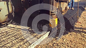 Asphalt paver machine lays asphalt mix on concrete base during road construction