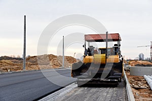 Asphalt paver machine during road work. Road Machinery at construction site for paving works. Screeding the sand for road