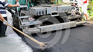 Asphalt paving machine, people. Paver, paving machine. Worker leveling asphalt