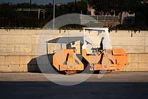 Asphalt paving machine with prominent shadow cast on the wall behind