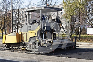 An asphalt paving machine works in the city center in the fall. Repair of road surfaces in a modern city using specialized