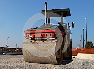 Asphalt paving machinery, in a road construction site. Front view of its roller