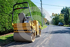 Asphalt paving roller sits empty on a suburban road and no workers