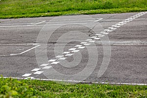 An asphalt racing track with a finish line among green grass and bushes. Horizontal orientation. High quality photo