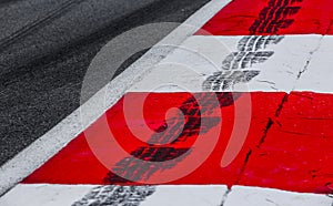 Asphalt red and white kerb of a race track detail with tire marks