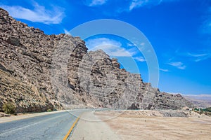 asphalt road along sand stone craggy desert rocks southwest dry landscape empty outside view