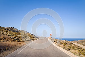 An asphalt road in the arid countryside and mountains , in Europe, Greece, Crete, towards Elafonisi, By the Mediterranean Sea, in