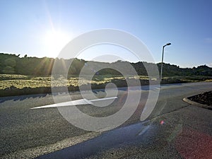 Asphalt road with an arrow and a turnoff in a stinted and rocky landscape in Iceland photo