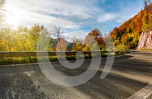 Asphalt road through autumn forest in mountains