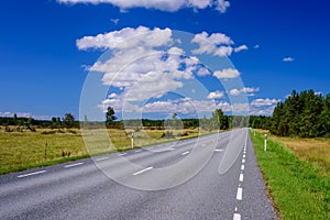 Asphalt road on the background of blue sky with clouds