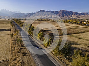 Asphalt road and car on high mountains background. aerial view