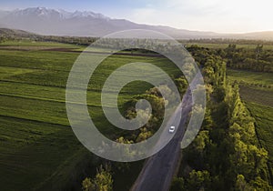 Asphalt road and car on high mountains background. aerial view