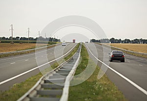 Asphalt road with cars , autumn wheat fields along the sides