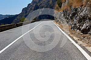 Asphalt road. Colorful landscape with beautiful mountain road with a perfect asphalt. High rocks, blue sky at sunrise in