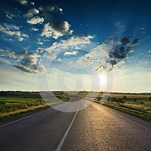 Asphalt road and dramatic clouds in dark sky in sunset