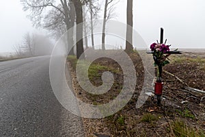 Asphalt road in the fog. Public road and cross commemorating a fatal accident