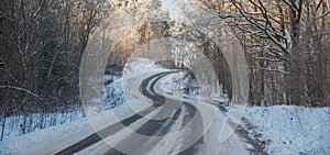 Asphalt road through forest covered with snow and ice. Difficult dangerous to drive. Winter troubles for drivers. Snowy winter.