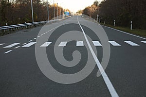 asphalt road in forest. White and black pedestrian crossing in rural area in Georgia. Zebra crossing or cross walk on empty