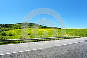 Asphalt road and green trees on hill